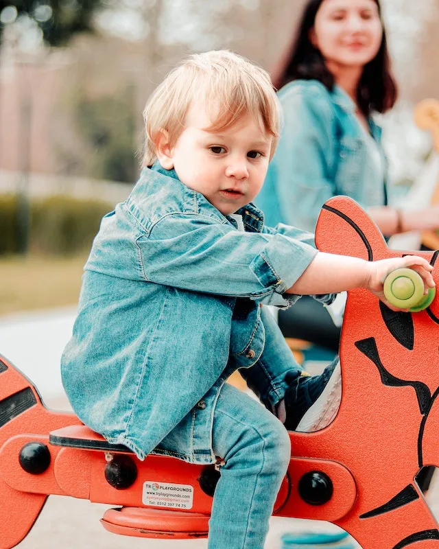 A toddler riding a rocker in the playground