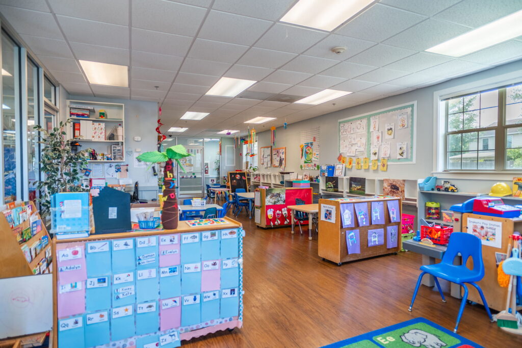 A classroom with a name chart, children’s drawings and a dramatic play station