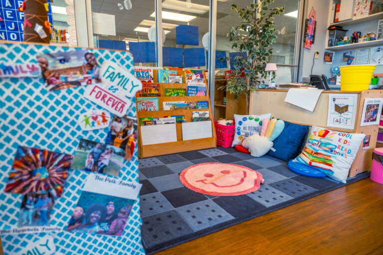 A reading corner with a picture-book rack, cushions and a family photo board