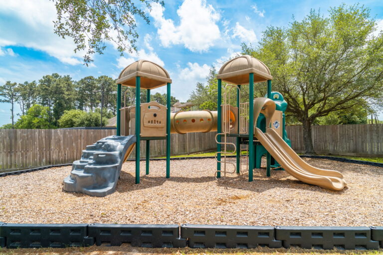 A playground climbing frame with a slide on a wood-chip surface